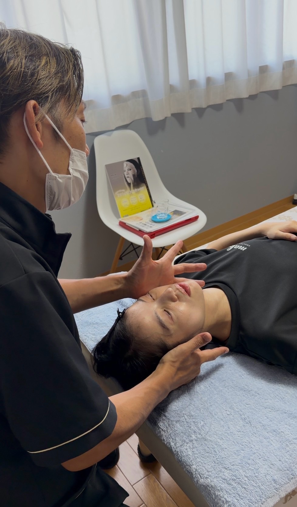施術室のベッドで顔まわりのケアを受けている様子